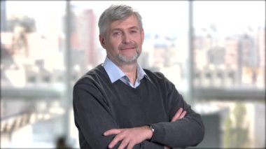 Kollarını kavuşturmuş olgun bir adam..