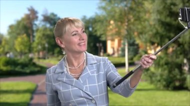 Orta yaşlı bir kadın alarak selfie açık havada.