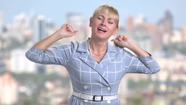 Middle-aged woman is yawning on blurred background. — Stock Video