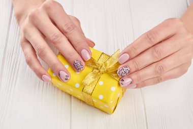 Erkek manikürlü eller ve hediye kutusu.