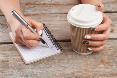 Manikürlü el üstünde defter yazma.