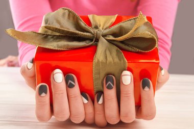 Erkek manikürlü eller ve hediye kutusu.