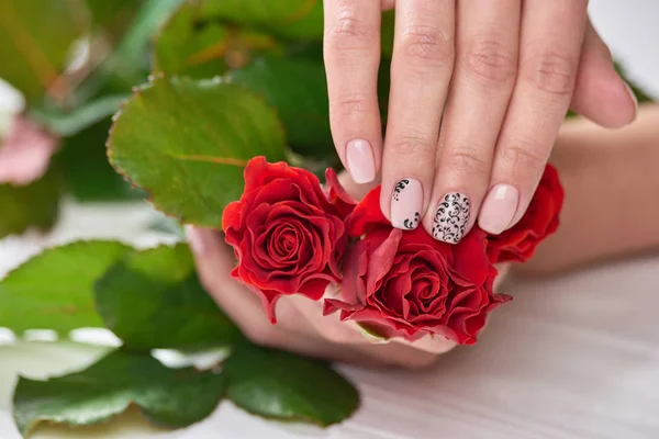 Female manicured hands holding roses.