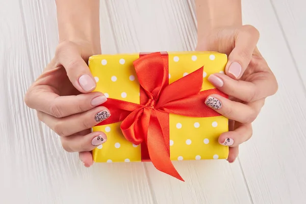 Scatola regalo punteggiata gialla nelle mani femminili . — Foto Stock