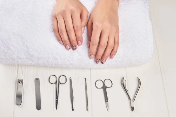 Female manicured hands on towel.