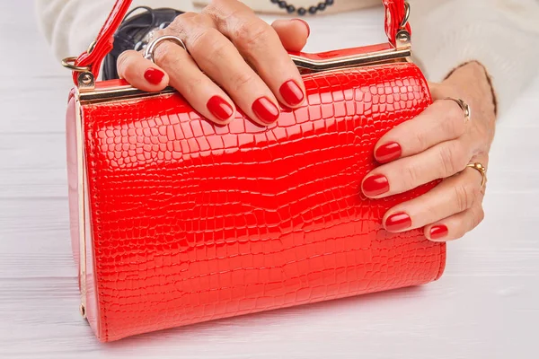 Bolso lacado rojo en manos femeninas . — Foto de Stock