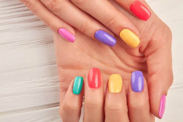 Vrouw handen met veelkleurige nagellak. — Stockfoto