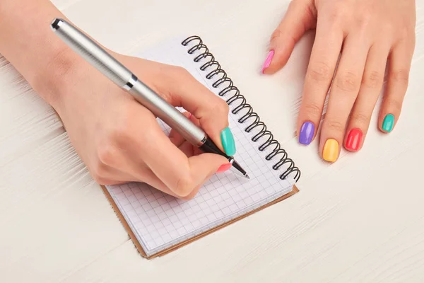 Mão com manicure de verão escrevendo no caderno . — Fotografia de Stock