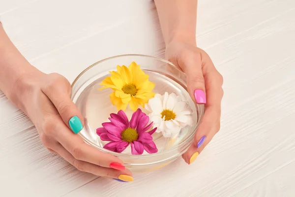 Bol en verre avec des fleurs dans les mains féminines . — Photo