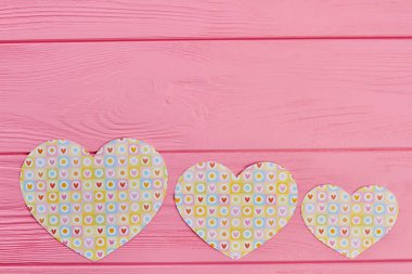 Three paper hearts on wooden background. clipart