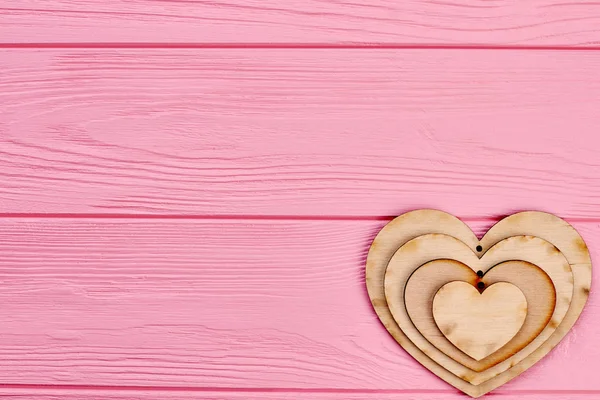 Corazones de madera en blanco sobre madera rosa . — Foto de Stock