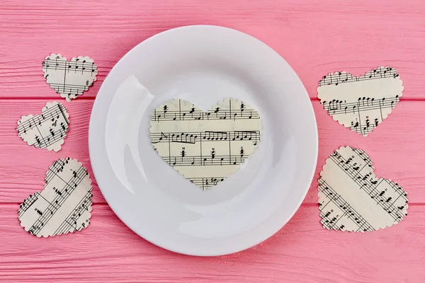 White plate and paper hearts with music notes.
