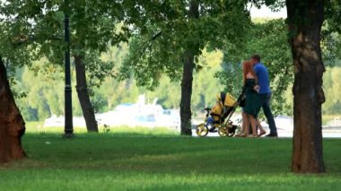 Aile bebek arabası ile parkta yürüyor.