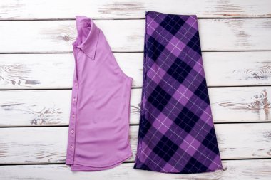 Pembe katlanmış gömlek ve mor Damalı etek.