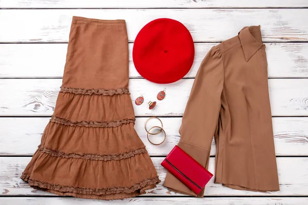 Braune Kleidung, rotes Portemonnaie und Baskenmütze. — Stockfoto