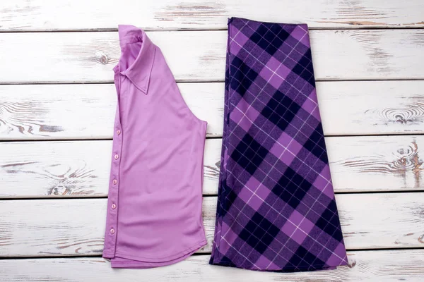 Pembe katlanmış gömlek ve mor Damalı etek.