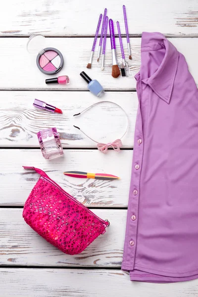 Kadınsı mor gömlek ve aksesuarları kolaj. Süslü pembe çanta. Arka plan beyaz ahşap masaları yüzey.