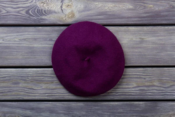 Chapéu de boina roxo no fundo de madeira escura . — Fotografia de Stock