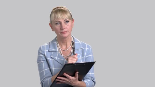 Serious mature female inspector writing on clipboard. — Stock Video