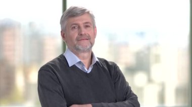 Çapraz kolları olan orta yaşlı beyaz işadamı portresi.