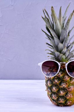 Hipster ananas ile güneş gözlüğü gri bir arka plana dayanır.