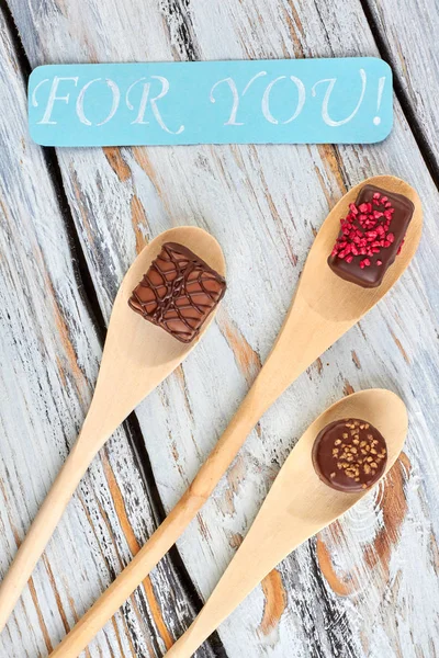 Wooden spoons with chocolate candies.