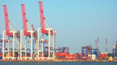 Rıhtımda mavi gökyüzünün üzerinde kargo vinçleri.