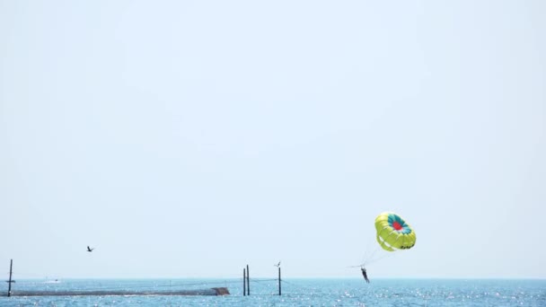 Hombre volando en un paracaídas amarillo sobre el mar . — Vídeos de Stock