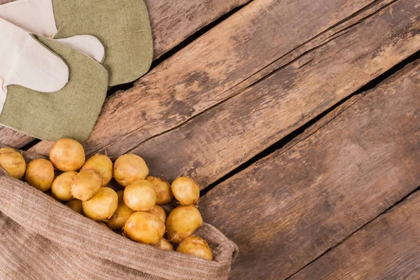 Mogen ung potatis i en säckväv väska och vantar. — Stockfoto