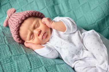 Kulaklarını kapsayan onun arkasında yatan kız bebek.