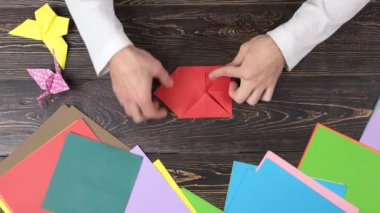 El ile kırmızı kağıt origami çiçek yapma.