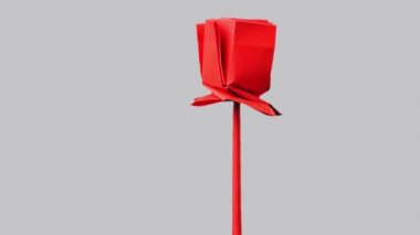 Gri arka plan üzerinde kırmızı origami çiçek.