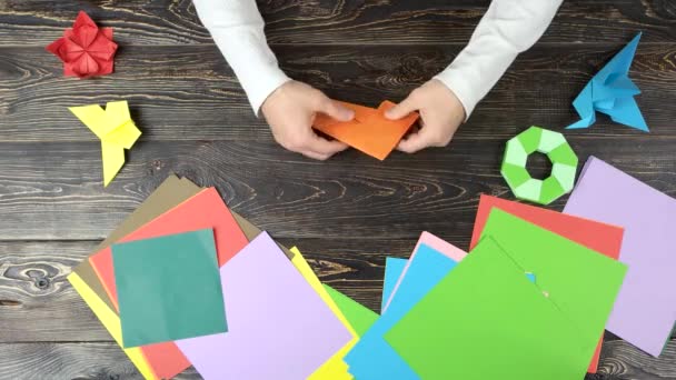 Manos de chico hacen grúa de origami con papel naranja . — Vídeos de Stock