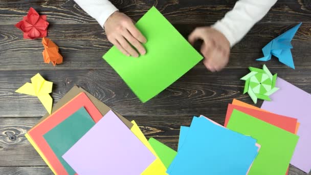 Manos de hombre hacen grúa de origami con papel verde . — Vídeo de stock