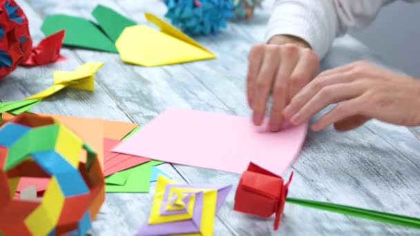 Criando origami com papel rosa . — Vídeo de Stock