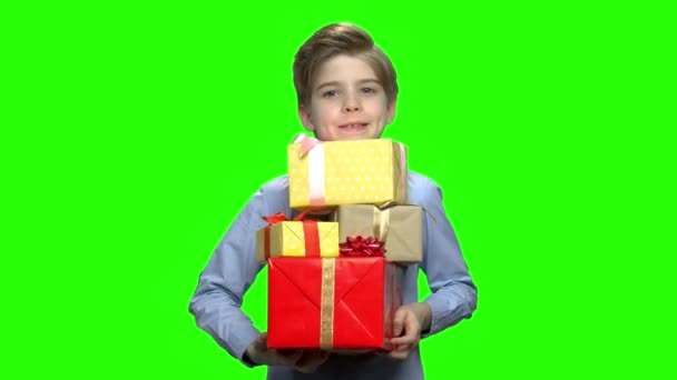 Porträt eines kleinen Jungen, der viele Geschenkboxen in seinen beiden Armen hält. — Stockvideo