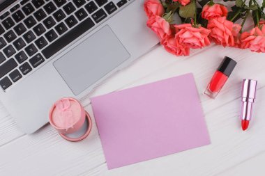 Makyaj ve iş kadın aksesuarları. Dizüstü bilgisayar, gül çiçek, lipstic, maskara, toz ve metin için boş kağıt. Beyaz tahta arka plan.