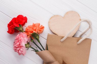 Gül çiçek ve shoppign çanta. Ahşap kalp. Beyaz tahta arka plan.