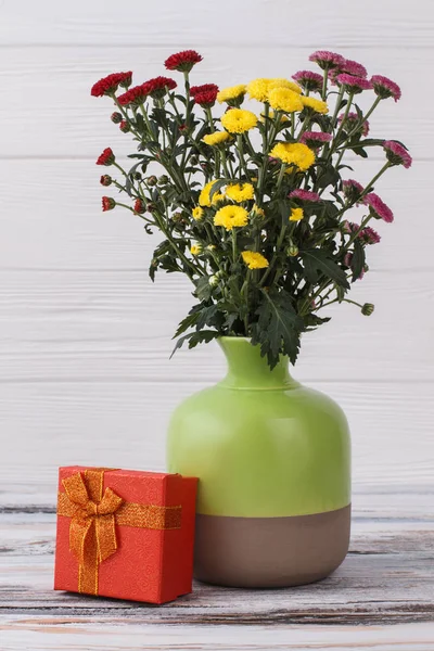 Πολύχρωμο chrysanthemus σε ένα βάζο και κόκκινο κουτί δώρου. — Φωτογραφία Αρχείου