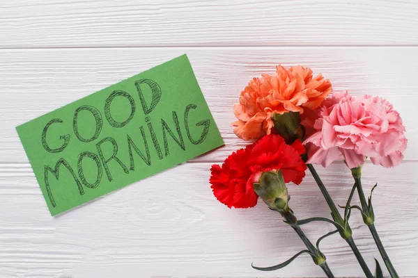 Buenos días nota deseo y flores de clavel de colores . — Foto de Stock