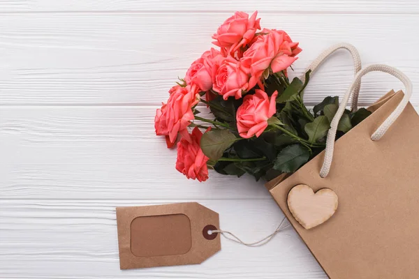 Μπουκέτο με ροζ τριαντάφυλλα, τσάντα για ψώνια και ετικέτα. — Φωτογραφία Αρχείου