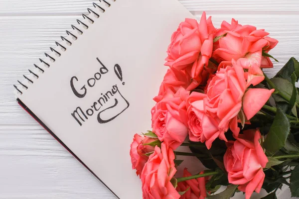 Rose flowers and good morning wish in notepad.
