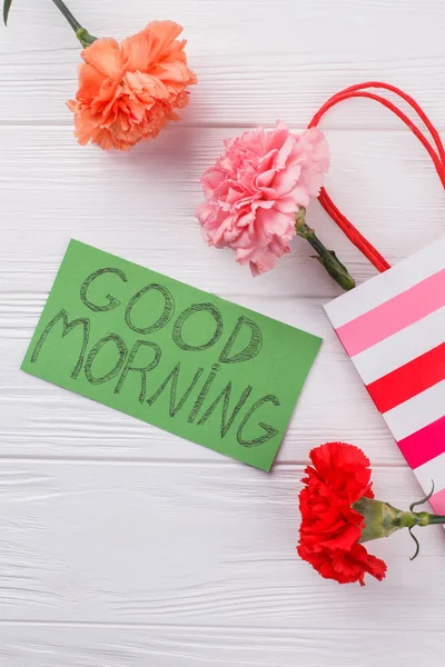 Flores de clavel coloridas y buen deseo de la mañana en la nota . — Foto de Stock