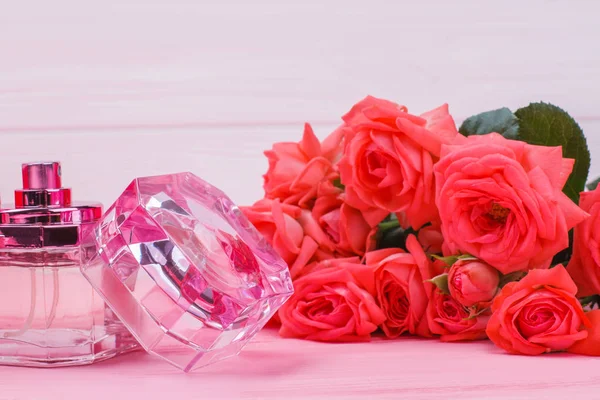 Perfume bottle and rose flowers close up. — Stock Photo, Image