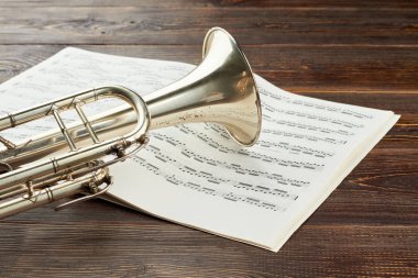 Trompet ve ahşap arka plan üzerinde müzik notaları.