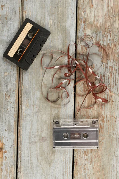 Two audio cassettes on wooden background.