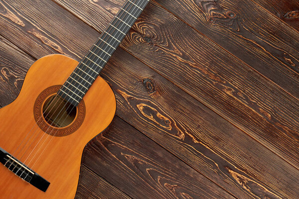 Acoustic guitar on textured wooden background.