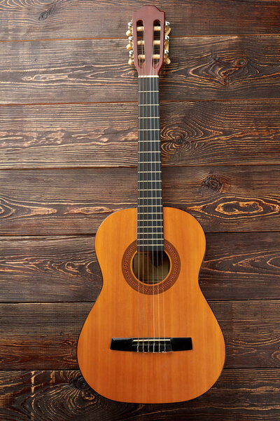 Acoustc guitar on brown wooden background.