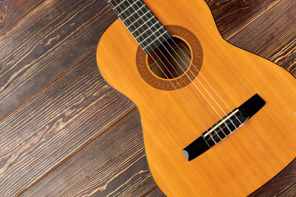 Guitar on brown wooden background.