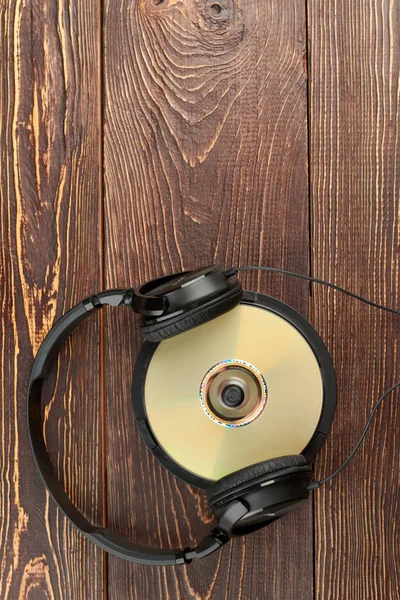 Cuffie e CD su sfondo in legno . — Foto Stock